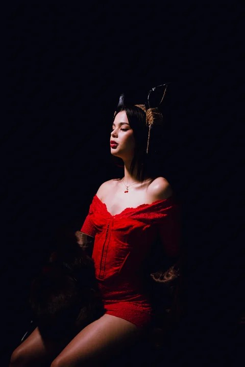 Retrato de una mujer con vestido rojo contra la oscuridad