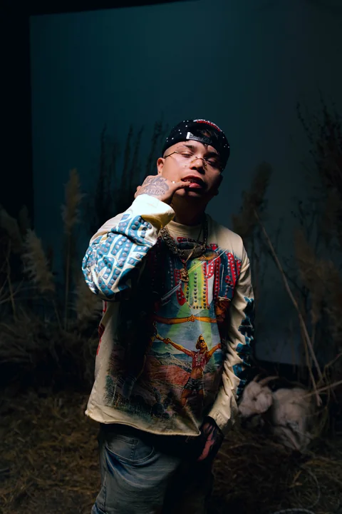 Artista con gorra entre vegetación y objetos de una puesta en escena