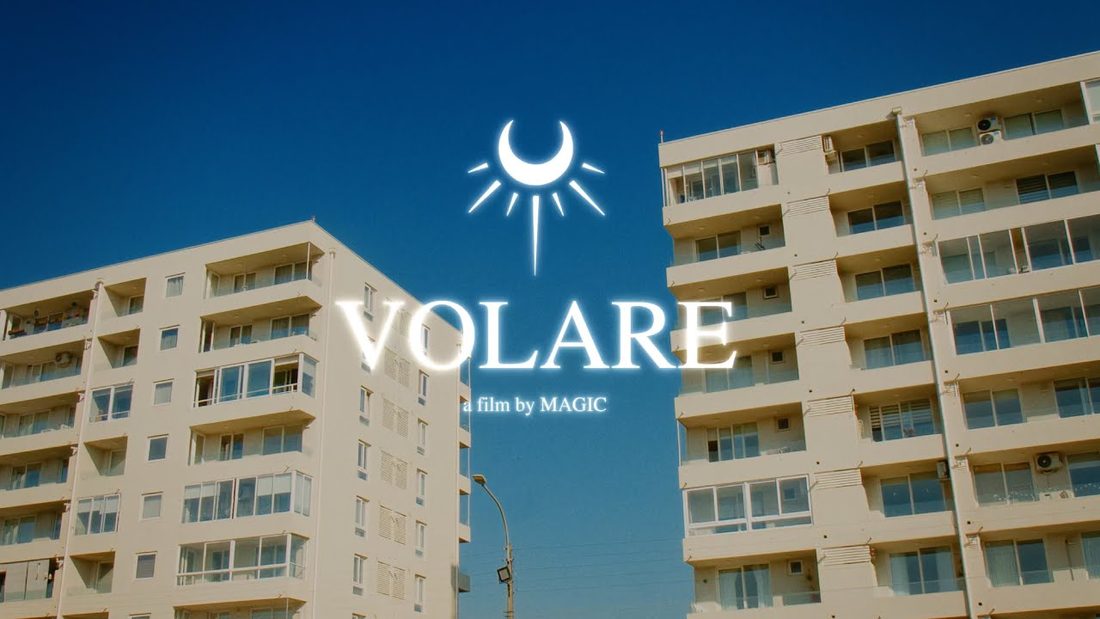 Fotograma de VOLARE: título sobre edificios blancos y cielo azul