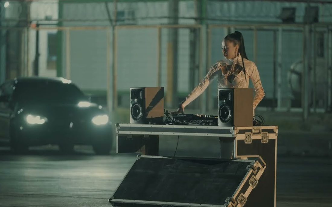 Fotograma del live set de Entropika: DJ frente a su equipo, con un auto de fondo
